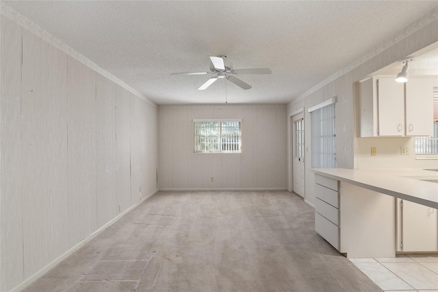 carpeted empty room featuring crown molding, a textured ceiling, and ceiling fan