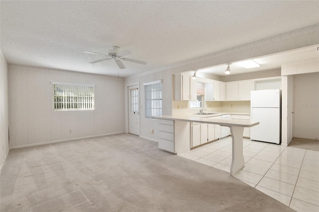 kitchen with white fridge, light carpet, ceiling fan, and white cabinets