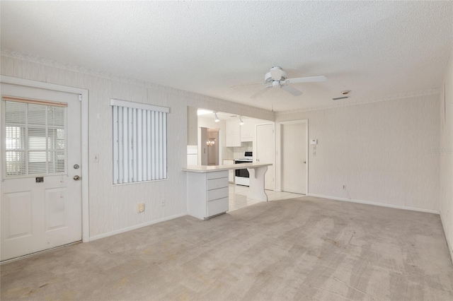 unfurnished living room with a textured ceiling, light colored carpet, and ceiling fan