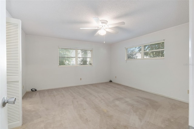 spare room featuring light carpet, a textured ceiling, and ceiling fan