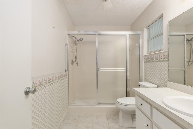 bathroom with toilet, tile patterned flooring, a shower with shower door, vanity, and a textured ceiling