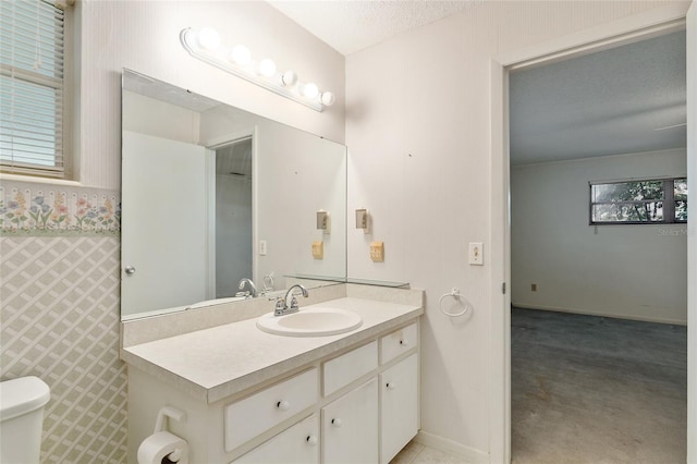 bathroom with toilet, a textured ceiling, and vanity