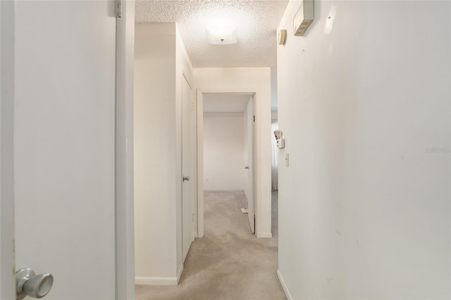 hallway featuring light carpet and a textured ceiling