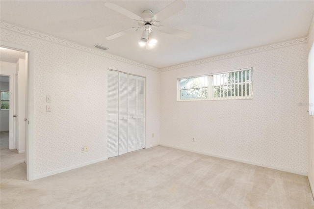 unfurnished bedroom with light carpet, a closet, and ceiling fan