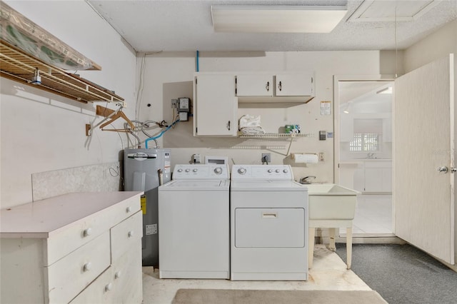 clothes washing area with sink, electric water heater, cabinets, and washer and clothes dryer