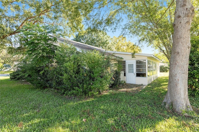 view of property exterior with a sunroom and a lawn