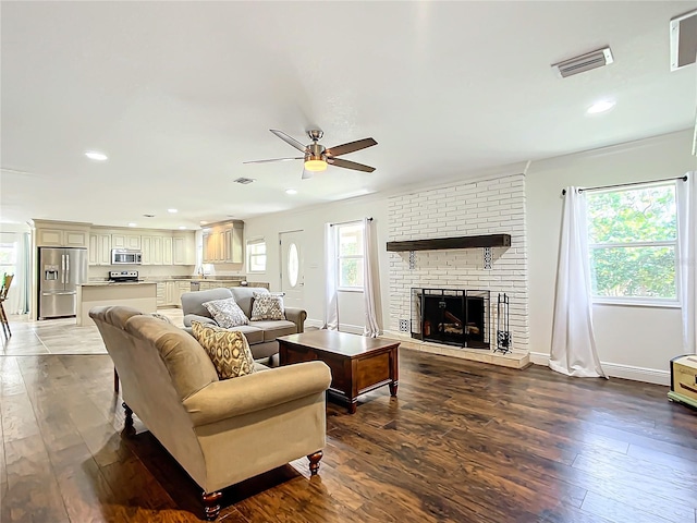 living room with a brick fireplace, hardwood / wood-style flooring, and ceiling fan