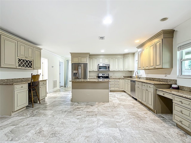 kitchen with appliances with stainless steel finishes, sink, a kitchen island, light stone counters, and ornamental molding