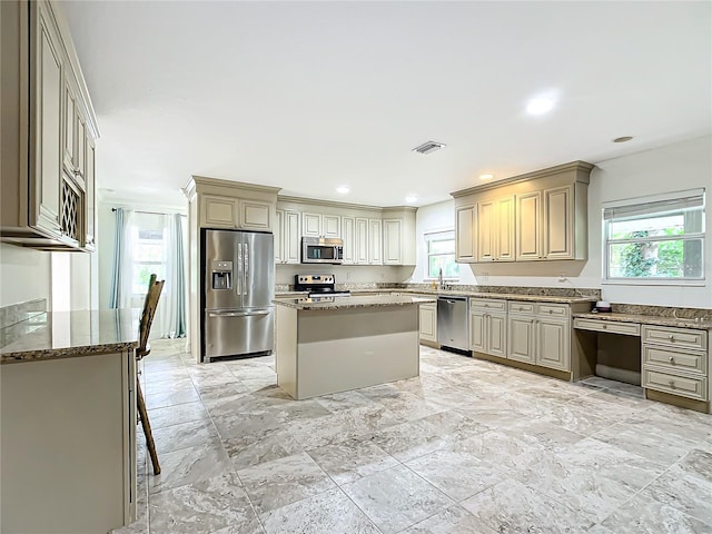 kitchen featuring appliances with stainless steel finishes, a center island, stone counters, and plenty of natural light