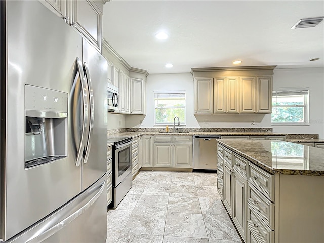 kitchen with stainless steel appliances, sink, stone countertops, and a wealth of natural light