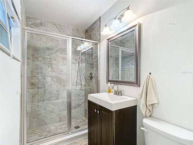 bathroom with vanity, toilet, a textured ceiling, and a shower with door