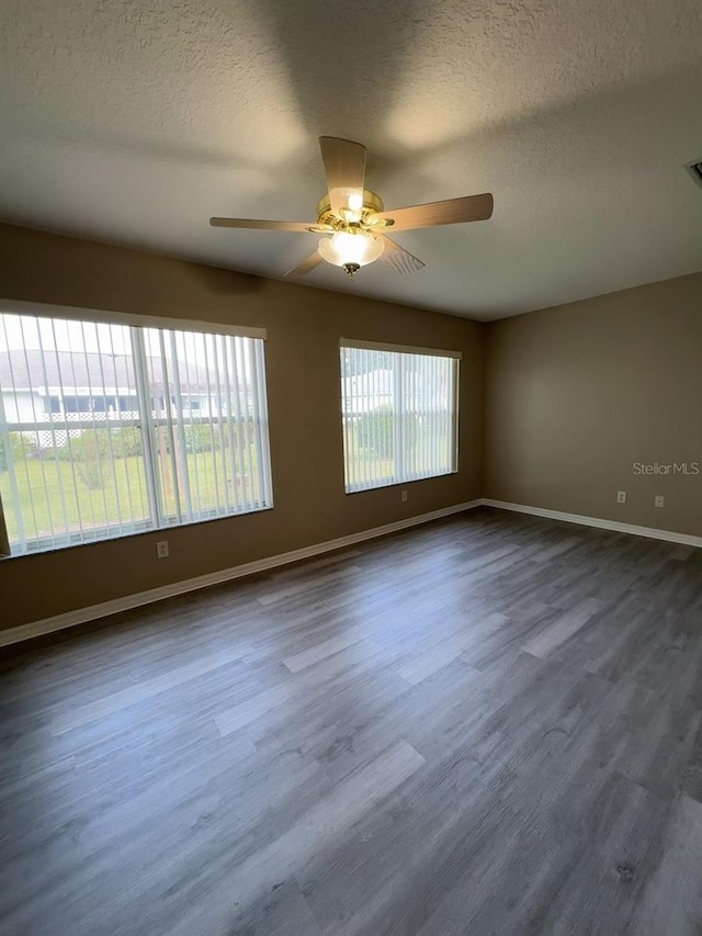 empty room with a textured ceiling, dark wood-type flooring, and ceiling fan