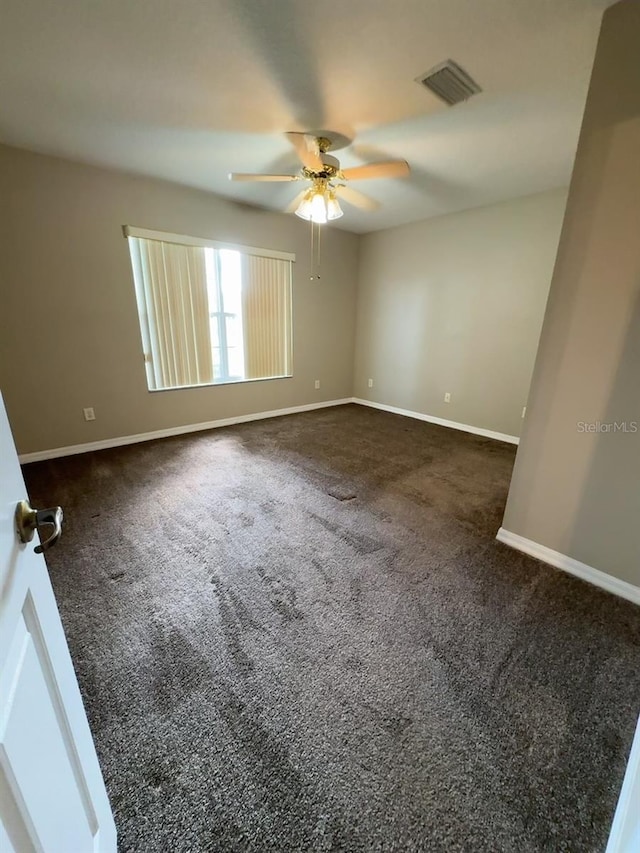 unfurnished room with ceiling fan and dark carpet