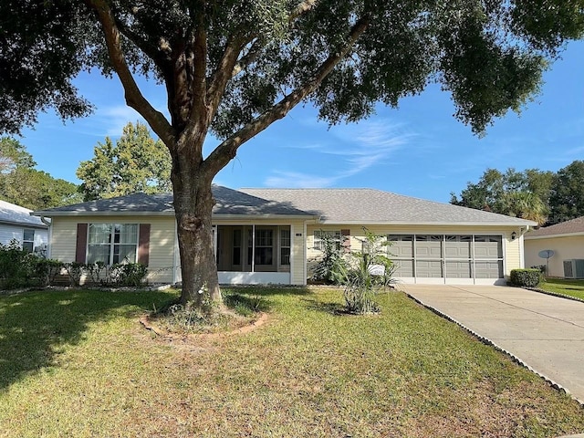 ranch-style house featuring a front yard, cooling unit, and a garage