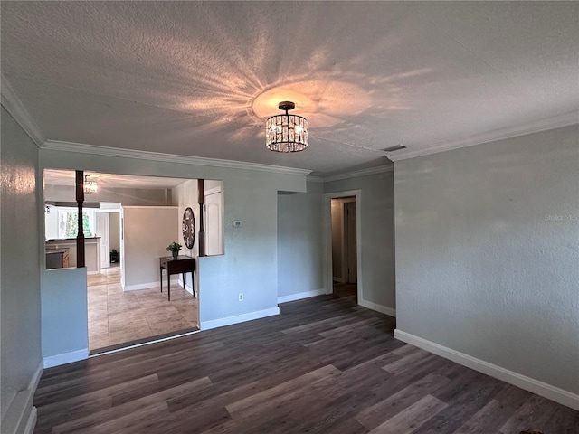 unfurnished room with ornamental molding, dark hardwood / wood-style flooring, a textured ceiling, and a notable chandelier