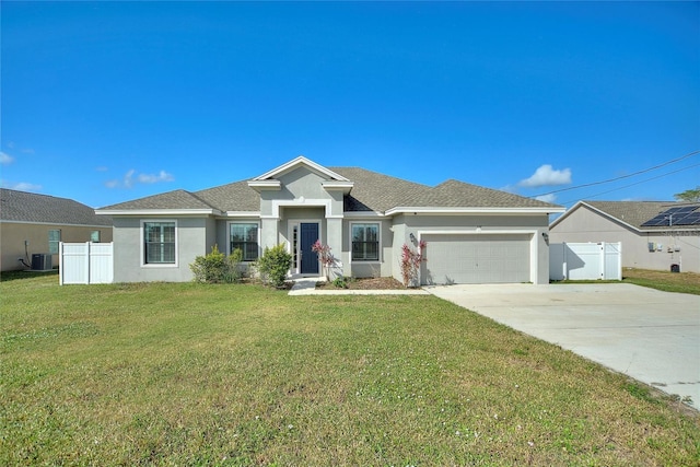 view of front of home with a front yard, central AC, and a garage