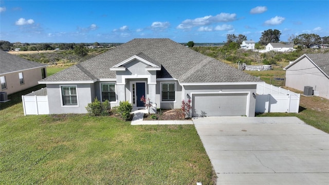 ranch-style home featuring a garage, a front lawn, and central AC unit