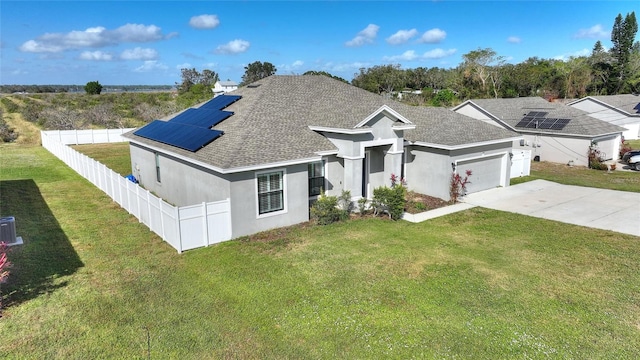 view of front of property with a front yard, solar panels, and a garage