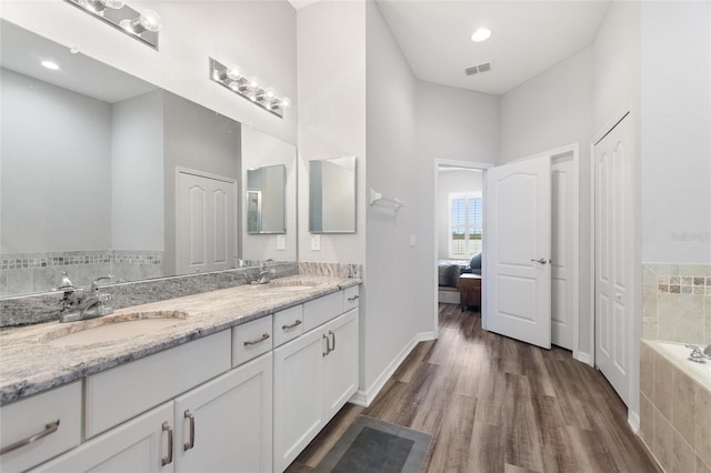 bathroom featuring vanity, a relaxing tiled tub, and hardwood / wood-style flooring