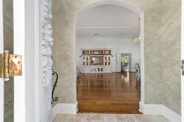 hallway with ornamental molding, hardwood / wood-style floors, and an inviting chandelier