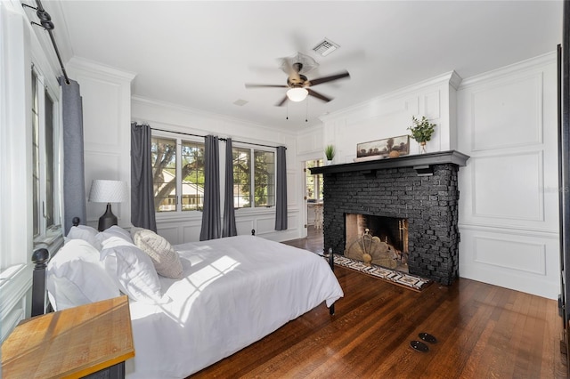 bedroom featuring ceiling fan, ornamental molding, dark hardwood / wood-style flooring, and a brick fireplace