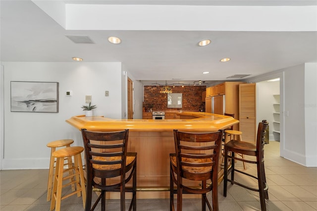 bar featuring brick wall, white stove, light tile patterned floors, and paneled fridge