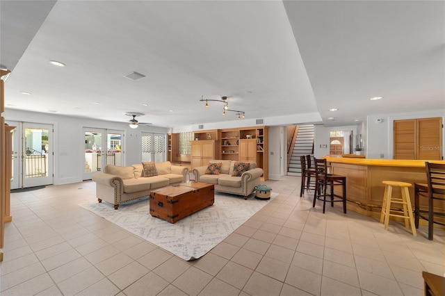 tiled living room with ceiling fan and indoor bar