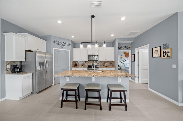 kitchen with a kitchen island with sink, hanging light fixtures, white cabinets, and stainless steel appliances