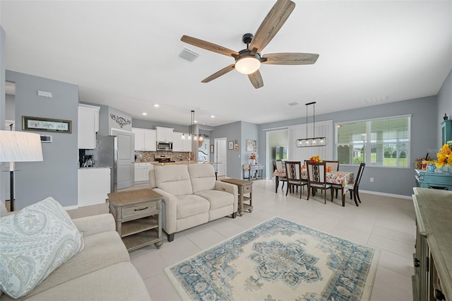 living room featuring light tile patterned floors and ceiling fan with notable chandelier