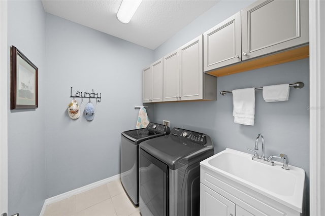 washroom featuring cabinets, sink, separate washer and dryer, a textured ceiling, and light tile patterned floors