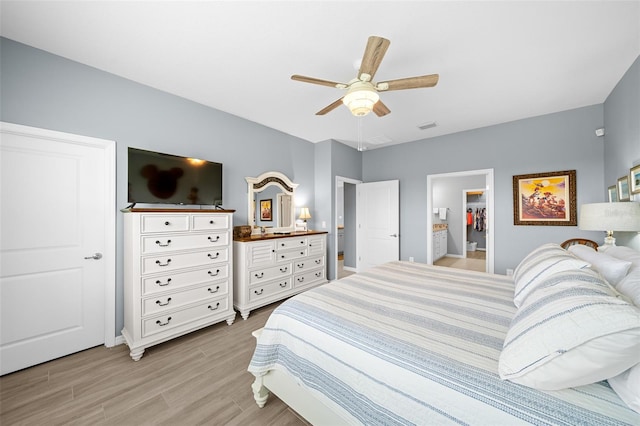 bedroom featuring ceiling fan, a spacious closet, light hardwood / wood-style flooring, connected bathroom, and a closet