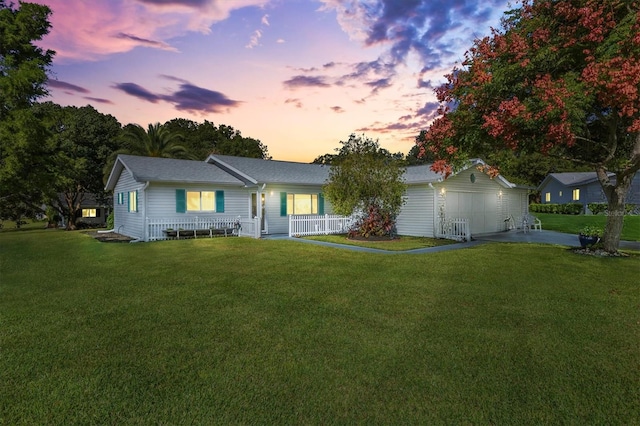 ranch-style house featuring a porch, a garage, and a yard