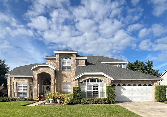 view of front facade with a shingled roof, concrete driveway, brick siding, and a front lawn