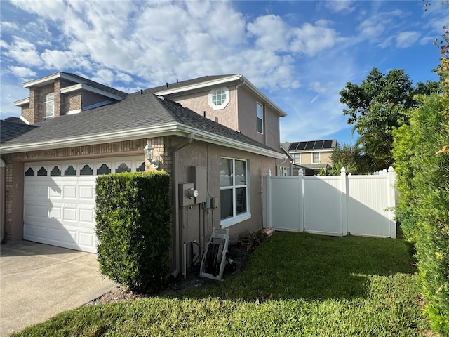 view of side of property with a yard, stucco siding, an attached garage, fence, and driveway