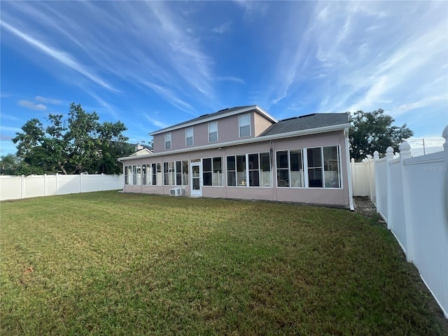 back of property with a sunroom, a fenced backyard, and a lawn