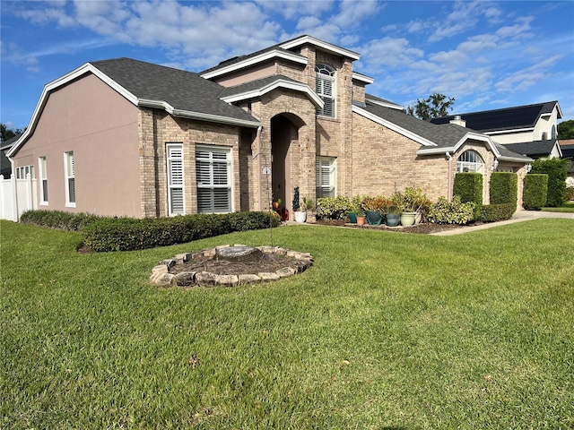 view of front of house with brick siding, a front lawn, and a shingled roof