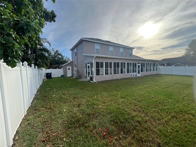 rear view of house with a lawn, a fenced backyard, a sunroom, and stucco siding