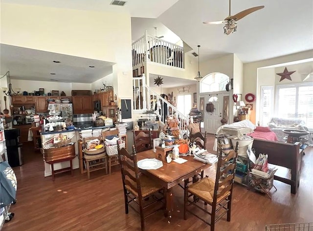 dining area with visible vents, a high ceiling, a ceiling fan, and wood finished floors