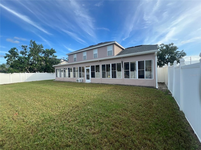 back of property with a lawn, a fenced backyard, a sunroom, and stucco siding