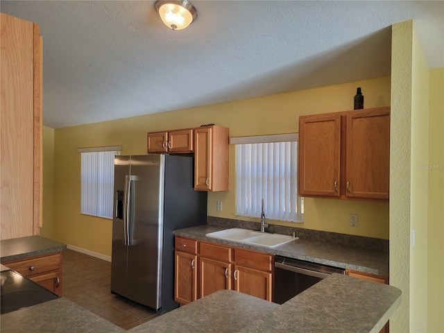 kitchen with sink, appliances with stainless steel finishes, a textured ceiling, and tile patterned flooring