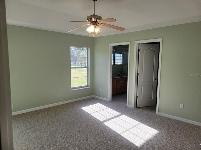 unfurnished bedroom featuring ensuite bath, light colored carpet, and ceiling fan