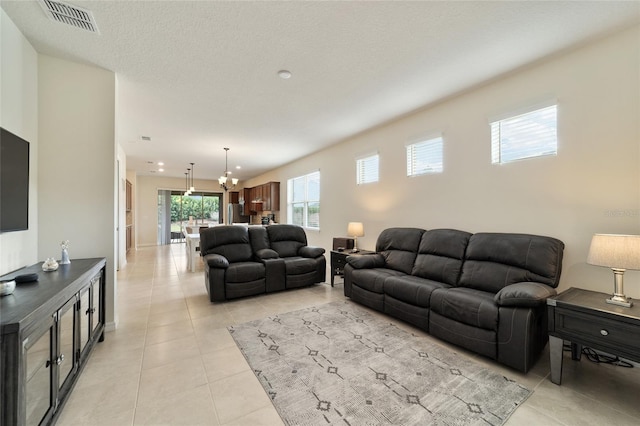 living room with a chandelier, a textured ceiling, and light tile patterned floors