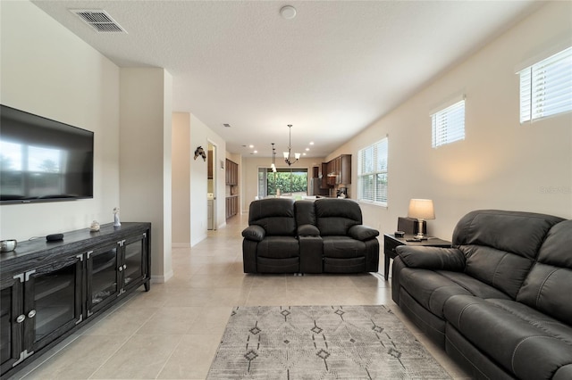 tiled living room with a textured ceiling and a chandelier