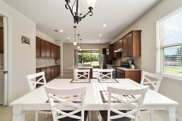 kitchen featuring a healthy amount of sunlight, decorative backsplash, decorative light fixtures, and stainless steel electric range oven