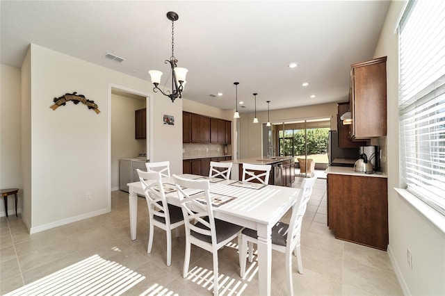 dining room featuring a chandelier, sink, separate washer and dryer, and light tile patterned floors