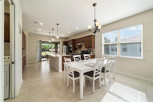 dining space featuring washer / clothes dryer, a chandelier, sink, and light tile patterned floors