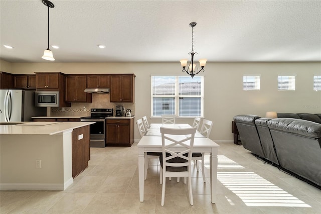 kitchen featuring backsplash, dark brown cabinets, stainless steel appliances, decorative light fixtures, and a chandelier