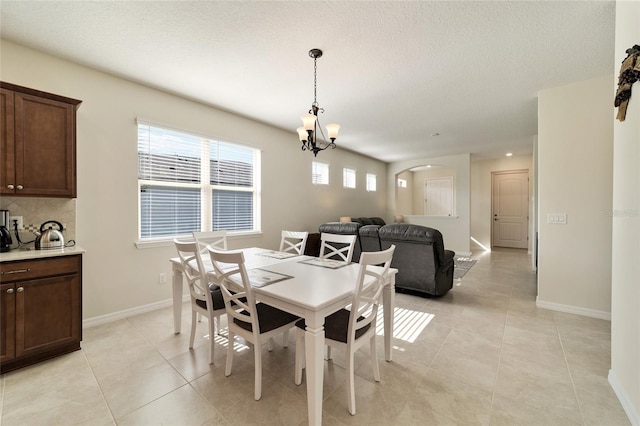 tiled dining room featuring a notable chandelier and a textured ceiling