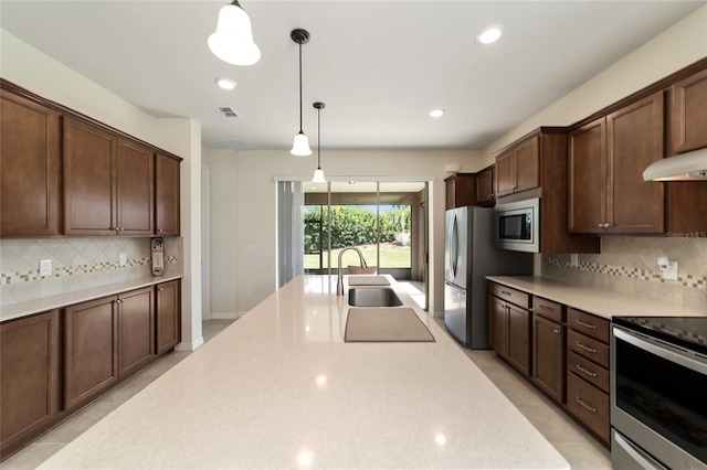 kitchen featuring appliances with stainless steel finishes, tasteful backsplash, decorative light fixtures, and sink