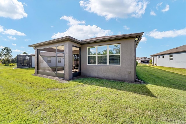 back of house featuring a sunroom and a lawn